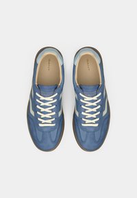 Μπλε σουέτ αθλητικά παπούτσια με ανοιχτό μπλε λεπτομέρεια και μπεζ διακοσμητικά. Διαθέτουν λευκά κορδόνια και καουτσούκ σόλα. Ορατό το λογότυπο της GANT.