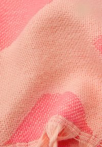 Tissu en coton tissé de couleur rose clair avec un motif à carreaux rose foncé, présentant une texture douce et des bords frangés.