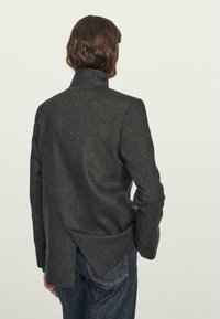 Czarny wełniany żakiet w kolorze ciemnoszarym z wysoką kołnierzem, wentylowanym tyłem i dopasowanym krojem. Charakteryzuje się minimalistycznym wzornictwem i prostymi liniami.