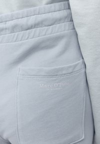 Světle modrý svetr z látky s texturovaným povrchem. Obsahuje náprsní kapsu s jemným potiskem loga v světlé barvě.