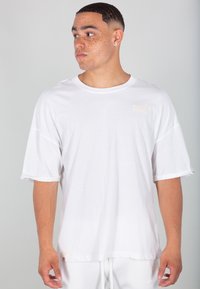 T-shirt bianco in cotone con scollatura rotonda, maniche corte e orlo dritto. Presenta un piccolo etichetta testurizzata sul petto.