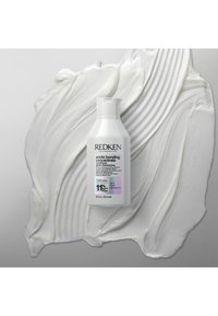 Weiße Flasche mit dem Redken Acidic Bonding Concentrate Conditioner, 300 ml, vor einem strukturierten, cremigen weißen Hintergrund. Klare Etikette mit schwarzem Text.
