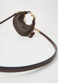 Sac bandoulière en cuir marron foncé en forme de croissant avec des ferrures dorées, fermeture éclair et bandoulière réglable sur fond blanc.