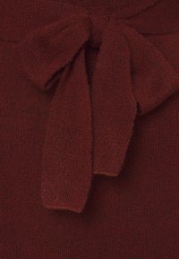 Le tissu tricoté bourgogne présente un détail de nœud distinctif à la taille, avec une finition douce et texturée et une apparence chaleureuse.