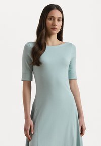 Knee-length, vaaleansininen mekko, joka on valmistettu pehmeästä kankaasta. Mekossa on pyöreä pääntie, lyhyet hihat, joissa on käänteet, ja sivutaskut.