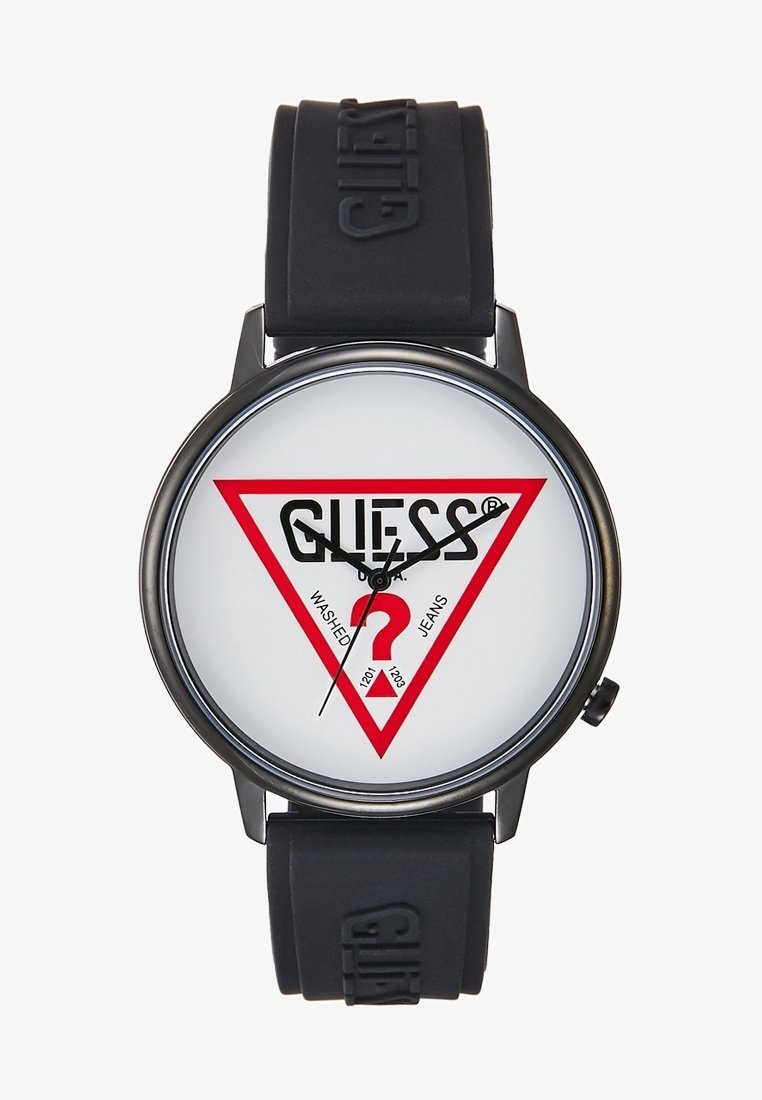Montre-bracelet ronde noire avec cadran blanc présentant un triangle rouge et le logo "GUESS", aiguilles des heures et des minutes noires, et bracelet en caoutchouc noir embossé "GUESS".
