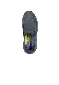 Zapato gris sin cordones con una parte superior de tela texturizada, punta redondeada y suela flexible. El interior cuenta con una plantilla acolchada en amarillo y azul.