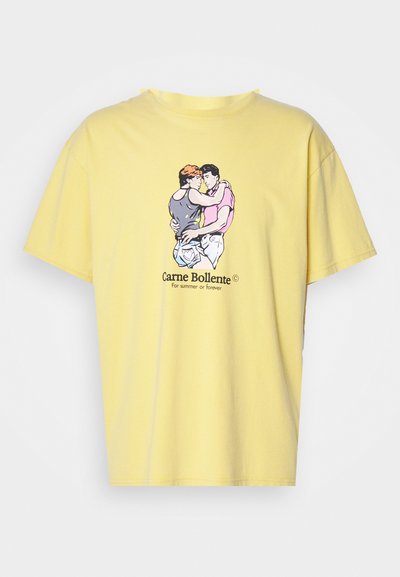 T-shirt de algodão amarelo com um corte solto, apresentando uma ilustração gráfica de duas figuras a abraçar-se. O nome da marca está impresso abaixo.