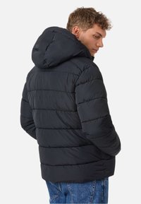 Czarna kurtka puchowa z kapturem, z pikowanymi sekcjami, gładką fakturą i lekko dopasowanym krojem. Widoczne detale szwów.