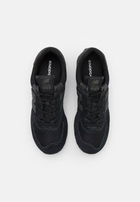 Adidași sport negri din materiale plasă și suede, cu șireturi, brandul "New Balance" și eticheta "Classic 574" pe limbă.