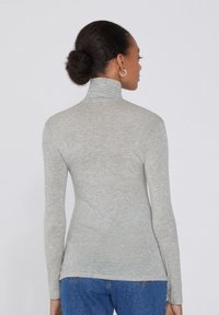Jasnoszary, długi rękaw, sweter z wysokim kołnierzem wykonany z miękkiego, teksturowanego materiału, charakteryzujący się dopasowanym krojem i wysokim kołnierzem.