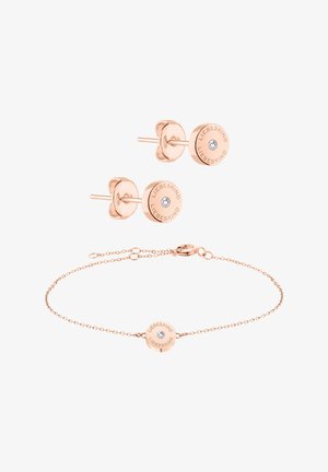 Smykkesæt i rosaguld med ørestikker med klar sten og matchende armbånd med en rund vedhæng, indgraveret logo og en fin kæde.