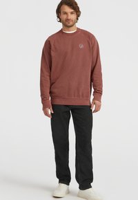 Bordeaux sweatshirt i bomuldsblanding, med rund halsudskæring og ribbede manchetter. Sammen med sorte jeans og hvide sneakers.
