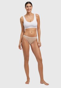 Weißes Crop-Top und beigefarbene Bikinihose aus weichem Stoff; mit Rundhalsausschnitt und kontrastierendem Bund. Glatte Textur und schlichtes Design.