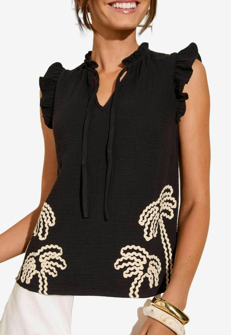 Blusa nera texturizzata con maniche a volant, scollatura a V e dettaglio con fiocco. Presenta un ricamo di palme color crema sulla parte anteriore inferiore.