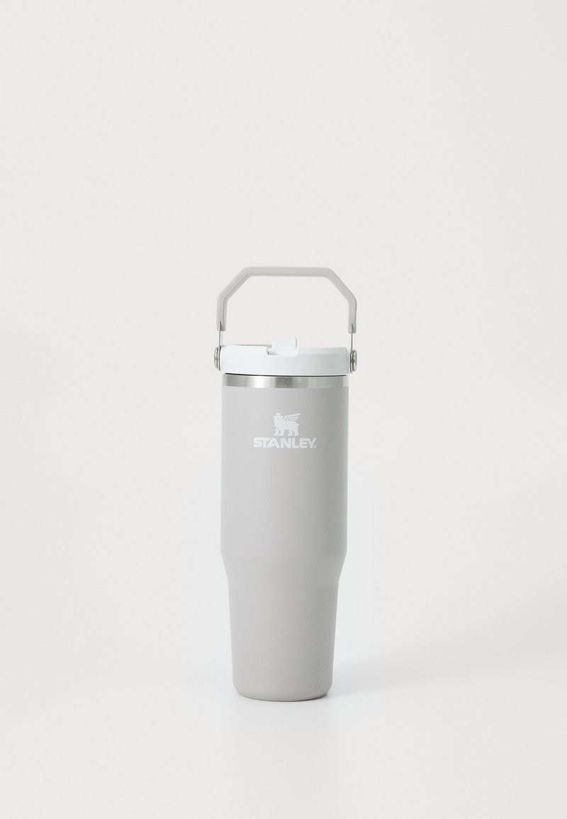 Gray stainless steel travel mug with a tapered design, white plastic lid, and a metal handle for easy carrying. Features a logo on the front.