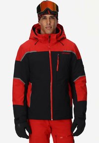 Rote und schwarze Skijacke mit Kapuze, mit reflektierenden Akzenten, einer Reißverschlusstasche und strukturiertem Material. Modell trägt Skibrille.