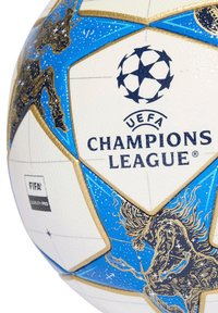 Un ballon de football UEFA Champions League blanc et bleu avec des panneaux en forme d'étoile et des illustrations dorées et noires détaillées sur les sections bleues.