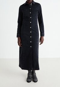 Mustat denimpitkä mekko napituksella etupuolella, kaksi rintataskua ja pitkät hihat. Yhdistetty harmaisiin nilkkureihin.