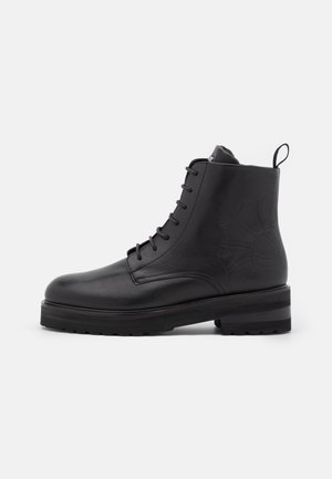 Bottines en cuir noir avec un bout rond, un design à lacets, des détails texturés sur les côtés et une semelle plateforme épaisse.