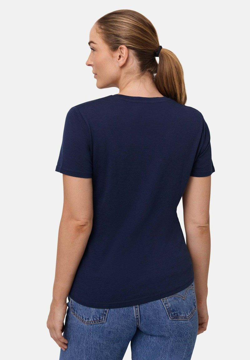 Mørkeblå kortærmet t-shirt med rund hals og glat tekstur, bærer med højtaljede blå jeans. Minimalistisk design, ingen mønstre.