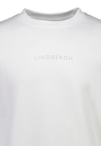 Vit bomulls-t-shirt med rundad halsringning och präglad text "LINDBERGH" på framsidan. Slät textur, minimalistisk design.