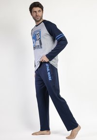 Camiseta de pijama de manga larga gris con detalles azul y gráfico de Star Wars, combinada con pantalones navy con "STAR WARS" impreso en azul.