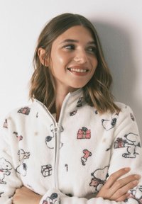 Biała polarowa kurtka z motywem Snoopy i wzorami prezentów, z przednim zamkiem błyskawicznym i miękką teksturą, idealna dla komfortu i ciepła.