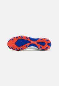 Suola di scarpini da calcio in bianco, rosso e blu. Presenta una superficie texturizzata con tacchetti circolari per la trazione. Sono presenti più fori di ventilazione.