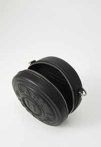 Round black leather bag with embossed logo, zip closure, and silver hardware. Interior is lined with black fabric. Textured finish.