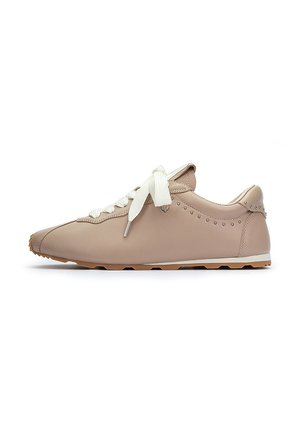 Zapatilla de cuero beige con punta redondeada, cordones blancos, tachuelas decorativas a lo largo del lateral y suela de goma texturizada.
