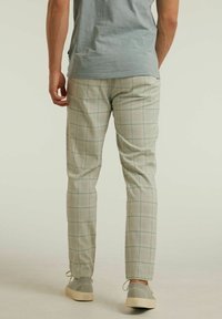 Ljust gröna rutiga byxor med en slim fit, med ett subtilt rutig mönster och en slät textur. I kombination med grå sneakers.