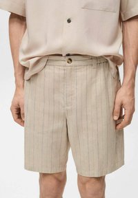 Beige shorts met een licht gestreept patroon, gemaakt van een gestructureerde stof. Voorzien van een knoopsluiting en zijzakken, met een relaxte pasvorm.
