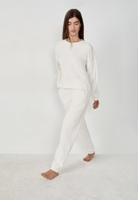 Ensemble de vêtements d'intérieur couleur crème comprenant un sweatshirt à coupe décontractée et un pantalon fuselé, fabriqué à partir d'un tissu doux, avec des poignets côtelés et sans motifs.