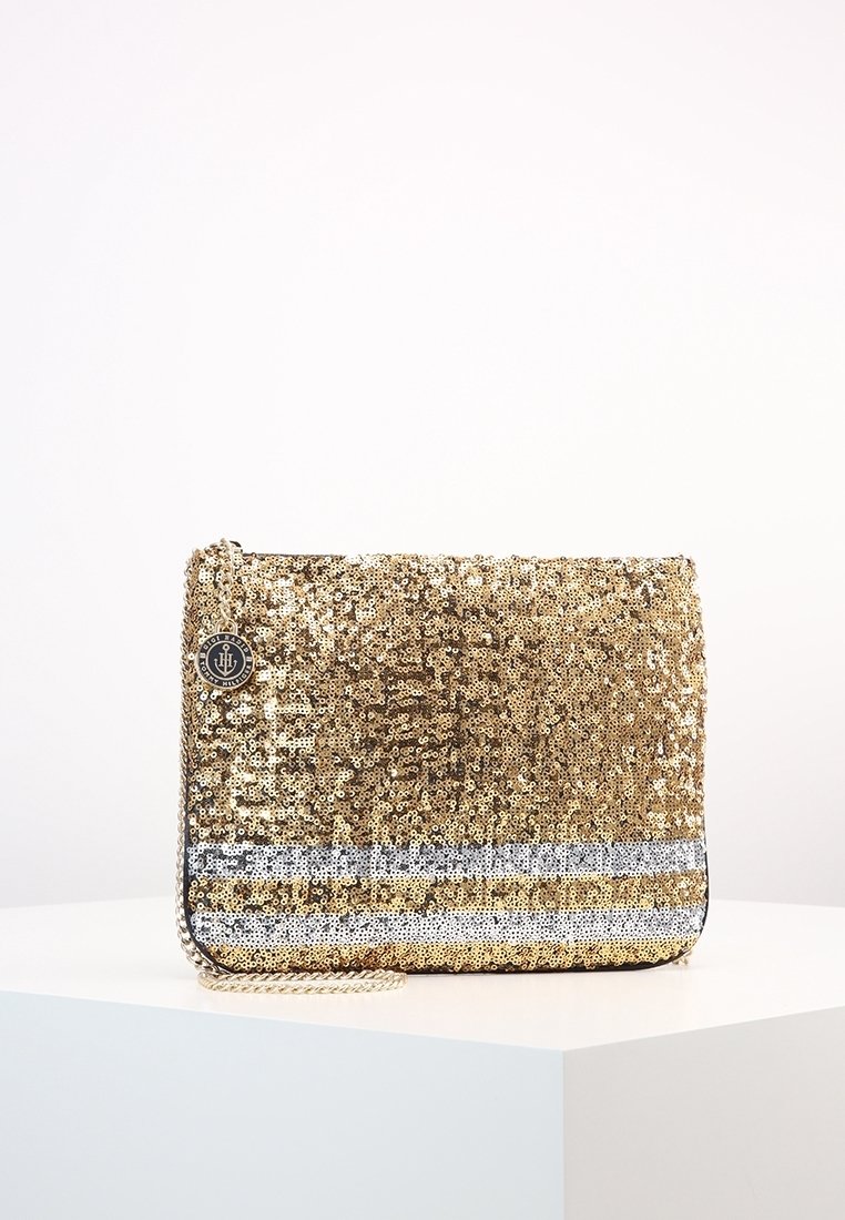 Kultainen paljettikukkaro, jossa on hopean- ja mustanväriset vaakaraitat, varustettu ketjunauhoilla ja sivulla oleva pyöreä logokiinnitys.