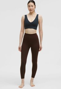 Hoge taille bruine leggings gecombineerd met een donkerblauwe sportbeha. De stof is glad met een aansluitend ontwerp, ideaal voor sportkleding.