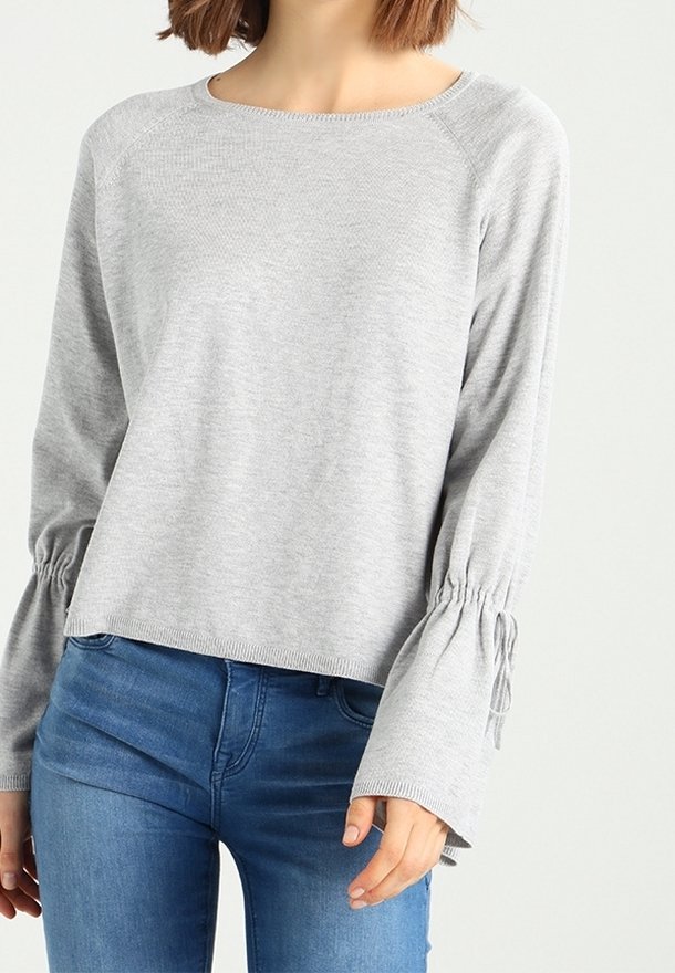 Pull tricoté gris clair avec un col rond, des manches raglan et des détails froncés aux poignets, associé à un jean bleu.