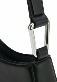 Bolso de mano de piel negra con una textura suave, que presenta un hebilla de metal plateado y detalles de correa, destacando líneas limpias y un diseño minimalista.