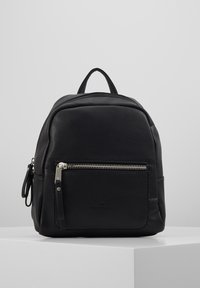 Sac à dos en cuir noir avec une surface texturée, doté d'une poignée supérieure et d'une poche zippée à l'avant, aux lignes épurées et aux accents en métal argenté.