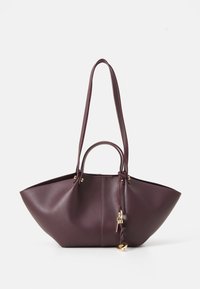 Sac fourre-tout en cuir bordeaux avec un design angulaire, deux longues sangles et une petite poignée. Présente des accents en métal doré et une fermeture à cordon.