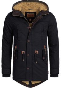 Veste d'hiver noire avec capuche doublée de fourrure, ornée d'accents marron, fermeture zippée et à boutons, et plusieurs poches. Tissu texturé.