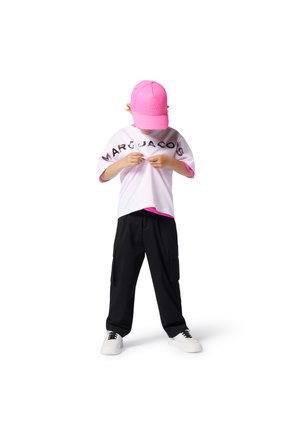 White t-shirt with pink accents, featuring "MARC JACOBS" in black text. Black cargo pants with pockets, white sneakers, and a pink cap.