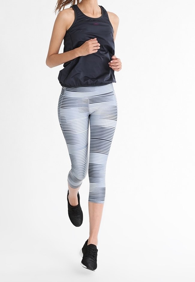 Czarny sportowy top bez rękawów, legginsy w szare i białe paski, czarne buty do biegania; lekkie materiały, dopasowany krój, legginsy do kolan.