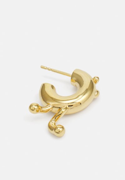 Gouden oorbel met een gebogen ontwerp, voorzien van een glad oppervlak, bolvormige accenten en een lange pin voor het bevestigen.