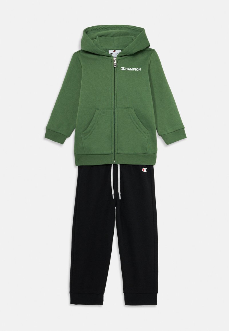 Πράσινο φούτερ με φερμουάρ και δύο μπροστινές τσέπες, σε συνδυασμό με μαύρη φόρμα με κορδόνι και λογότυπο στο πόδι. Μαλακή υφή υφάσματος.