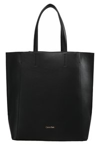 Czarna skórzana torba na ramię z pionowymi szwami, otwarta u góry, z dwiema rączkami. Posiada złote logo na środku na dole. Gładka faktura.