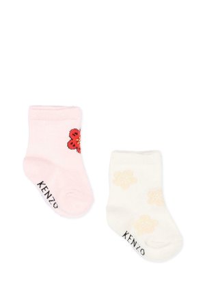 Dos calcetines de bebé, uno rosa claro con flor roja, otro crema con flores amarillo claro, ambos con el logo de KENZO en la suela.