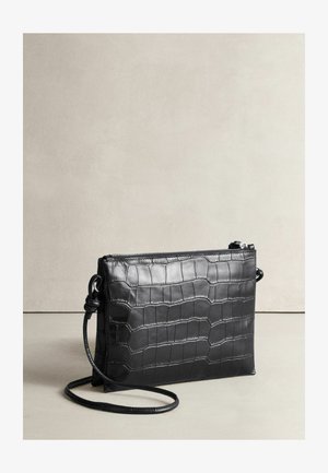 Black leather crossbody bag with a crocodile texture, zip closure, detachable strap, and minimalistic design, featuring a flat silhouette.