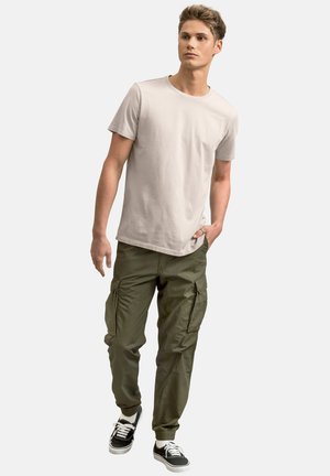 Maglietta a maniche corte grigia chiara con collo rotondo abbinata a pantaloni cargo verde oliva con tasche laterali, polsini elasticizzati e sneakers nere con lacci bianchi.