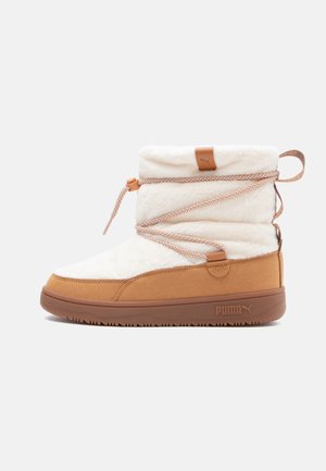 Botte d'hiver mi-haute avec dessus en polaire blanche, partie basse en suède beige, semelle beige et lacets à motifs enveloppants sur fond clair.